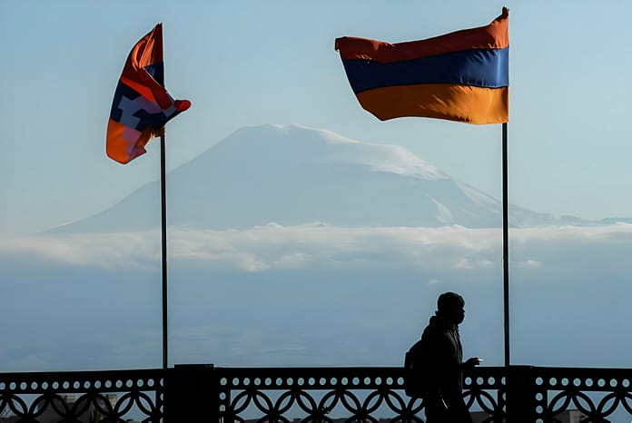 A man walks on a bridge decorated with flags of Armenia and the breakaway Nagorno-Karabakh region, with Mount Ararat on the background,Azerbaijan in Yerevan on October 7, 2020. (Photo by AFP) (Photo by -/AFP via Getty Images)